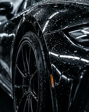 Illustrative dark vehicle exterior with water droplets and a front wheel